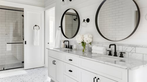 Bright bathroom with dual sinks and round mirrors in a Cape Cod, MA renovation by @designREMODEL