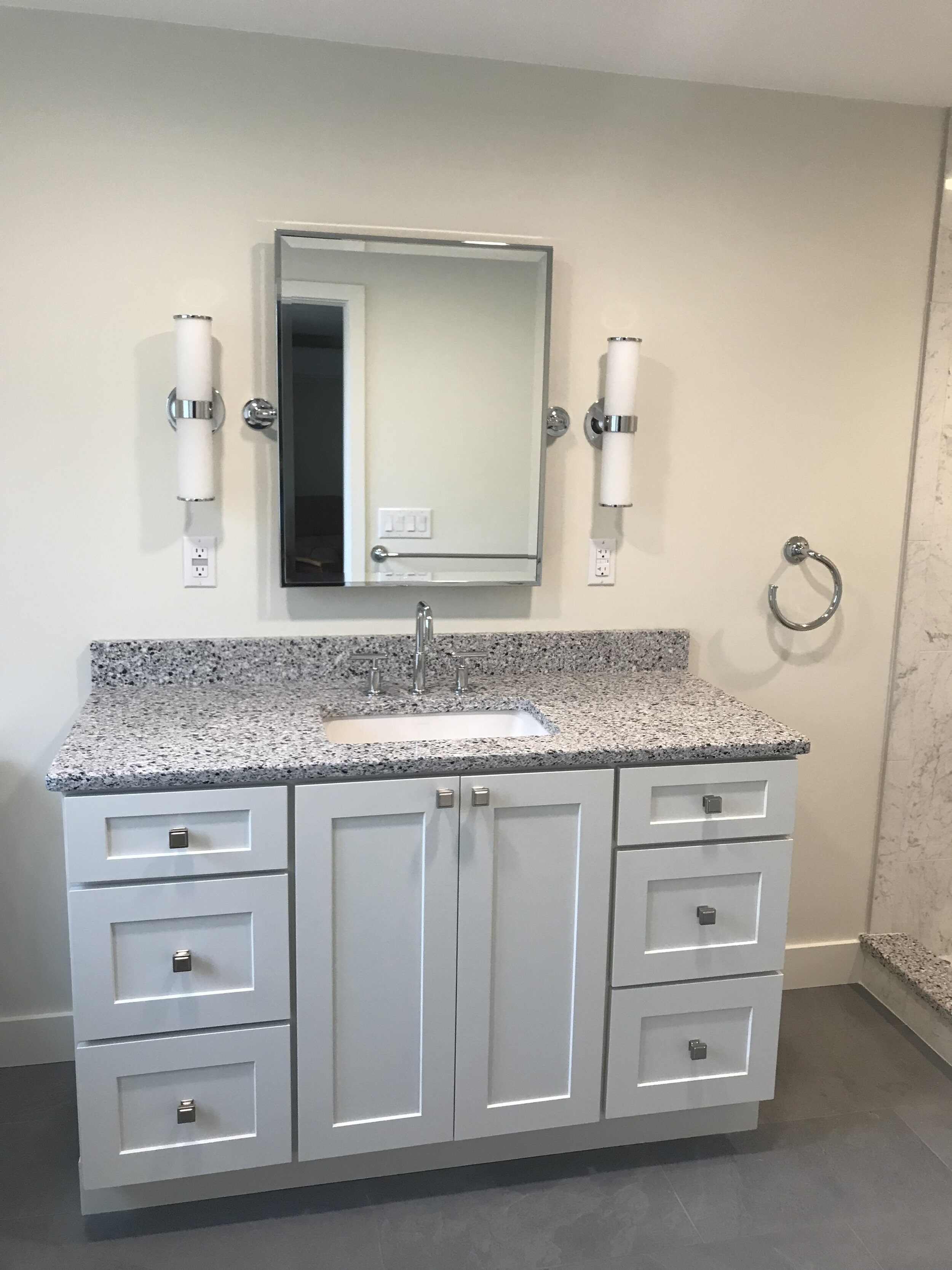 White Shaker style vanity with single sink in bathroom remodel.