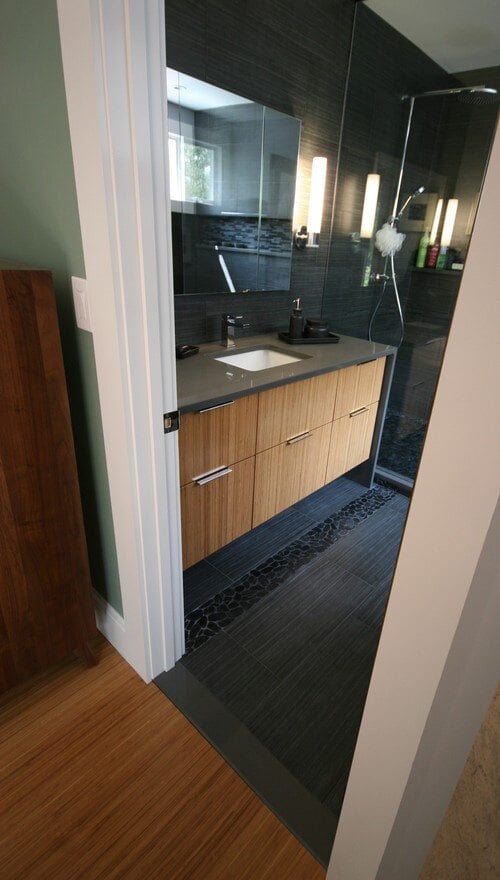 Sleek bathroom vanity in a Mashpee home remodel, featuring dark gray tiles and wooden drawers