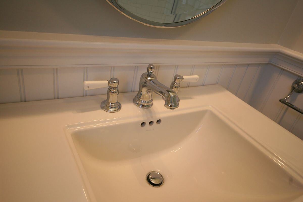 Close-up of Pin Oak Bath bathroom sink and chrome faucet by At Design Remodel, Mashpee