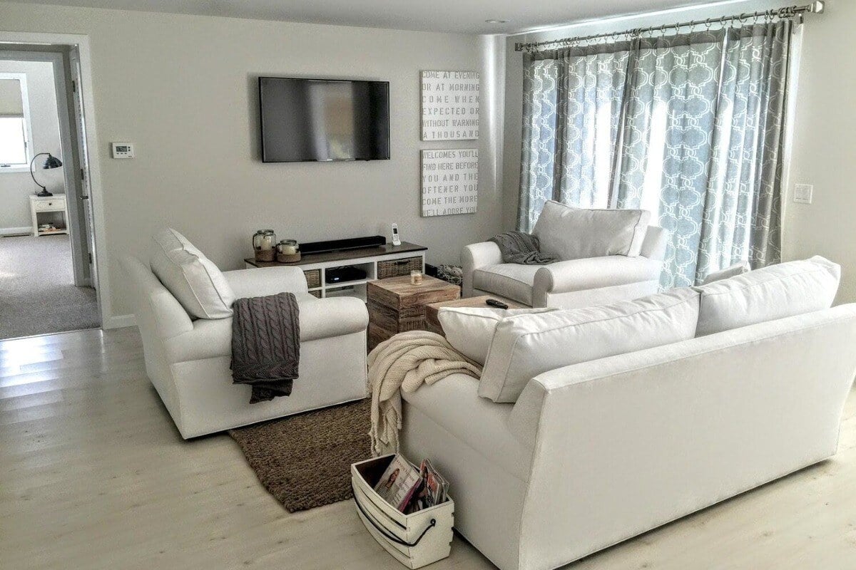 Bright living room with white sofas and light wood flooring in a Cape Cod home remodeled by @designREMODEL (1)-1