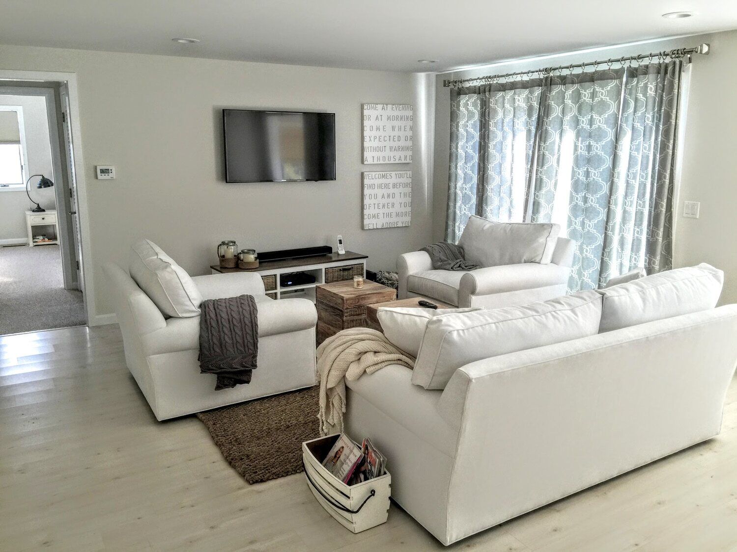 Bright living room with white sofas and light wood flooring in a Cape Cod home remodeled by @designREMODEL (1)