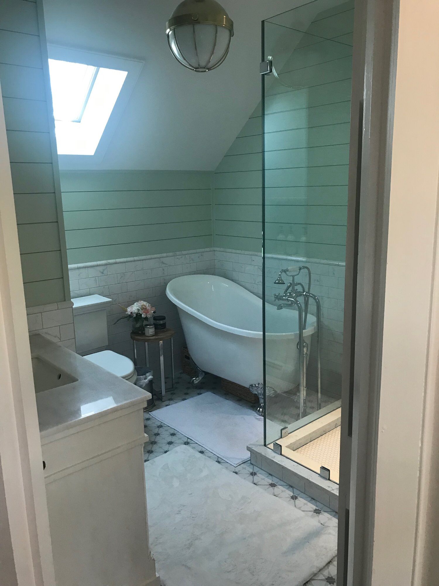 Charming bathroom with a clawfoot tub and skylight in a Cape Cod home remodeled by @designREMODE