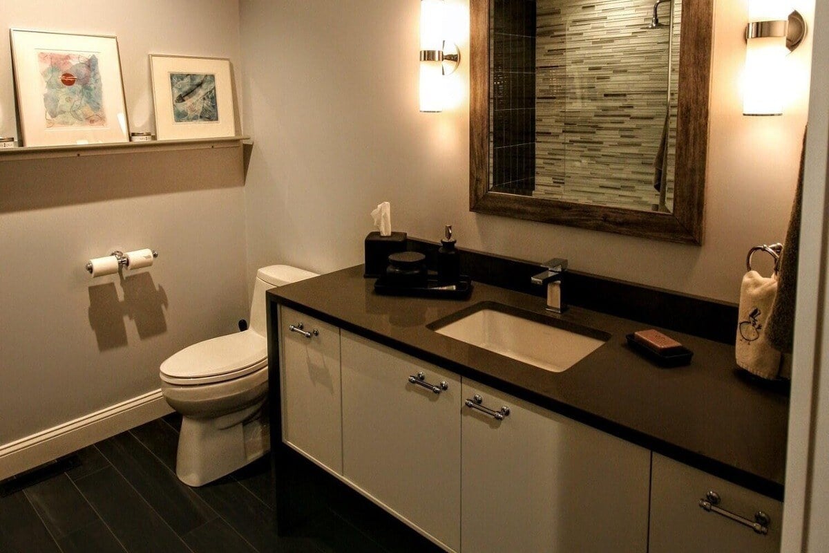 Elegant bathroom with dark flooring and modern fixtures in a Cape Cod home remodeled by @designREMODEL-1