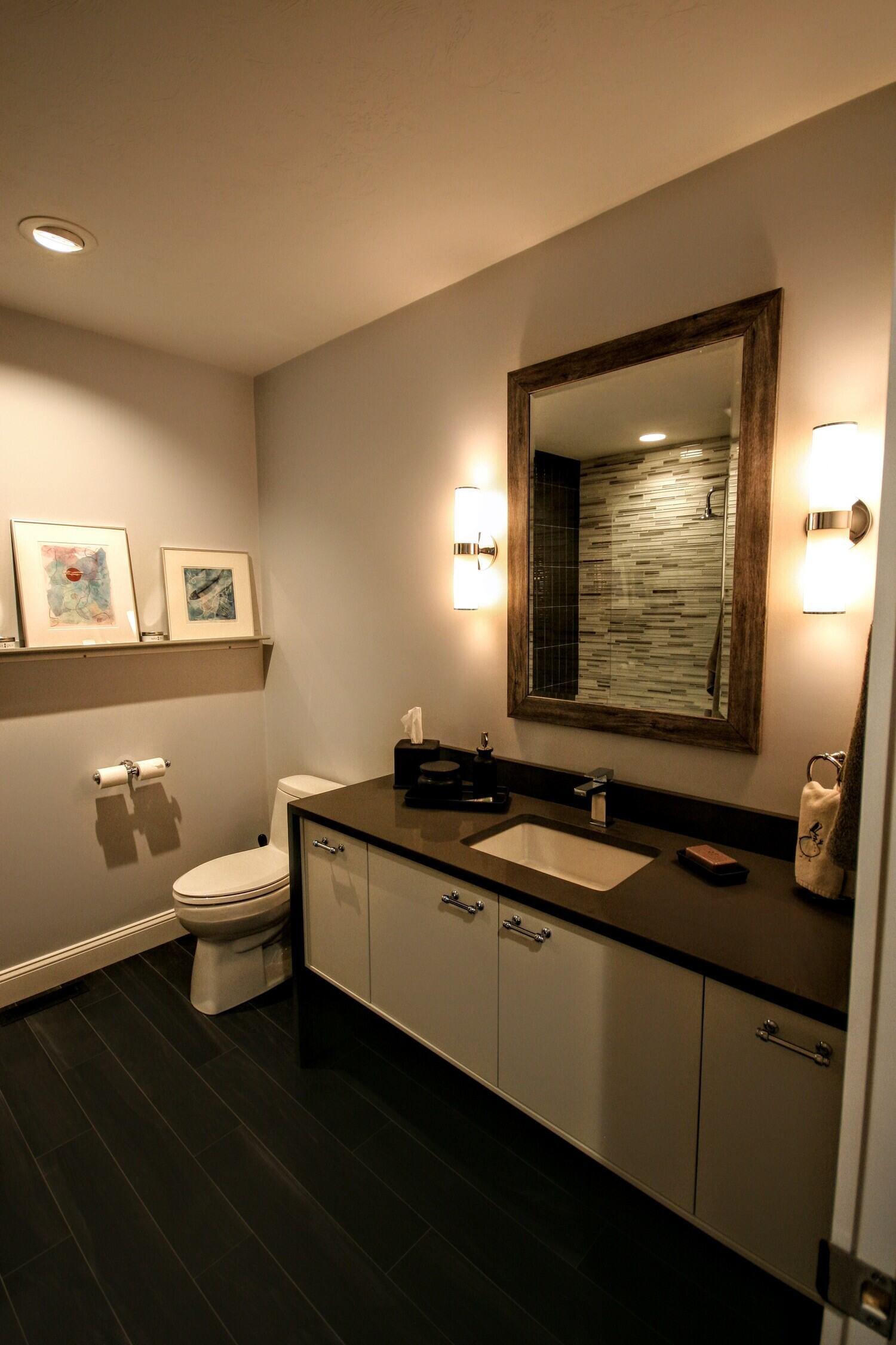 Elegant bathroom with dark flooring and modern fixtures in a Cape Cod home remodeled by @designREMODEL