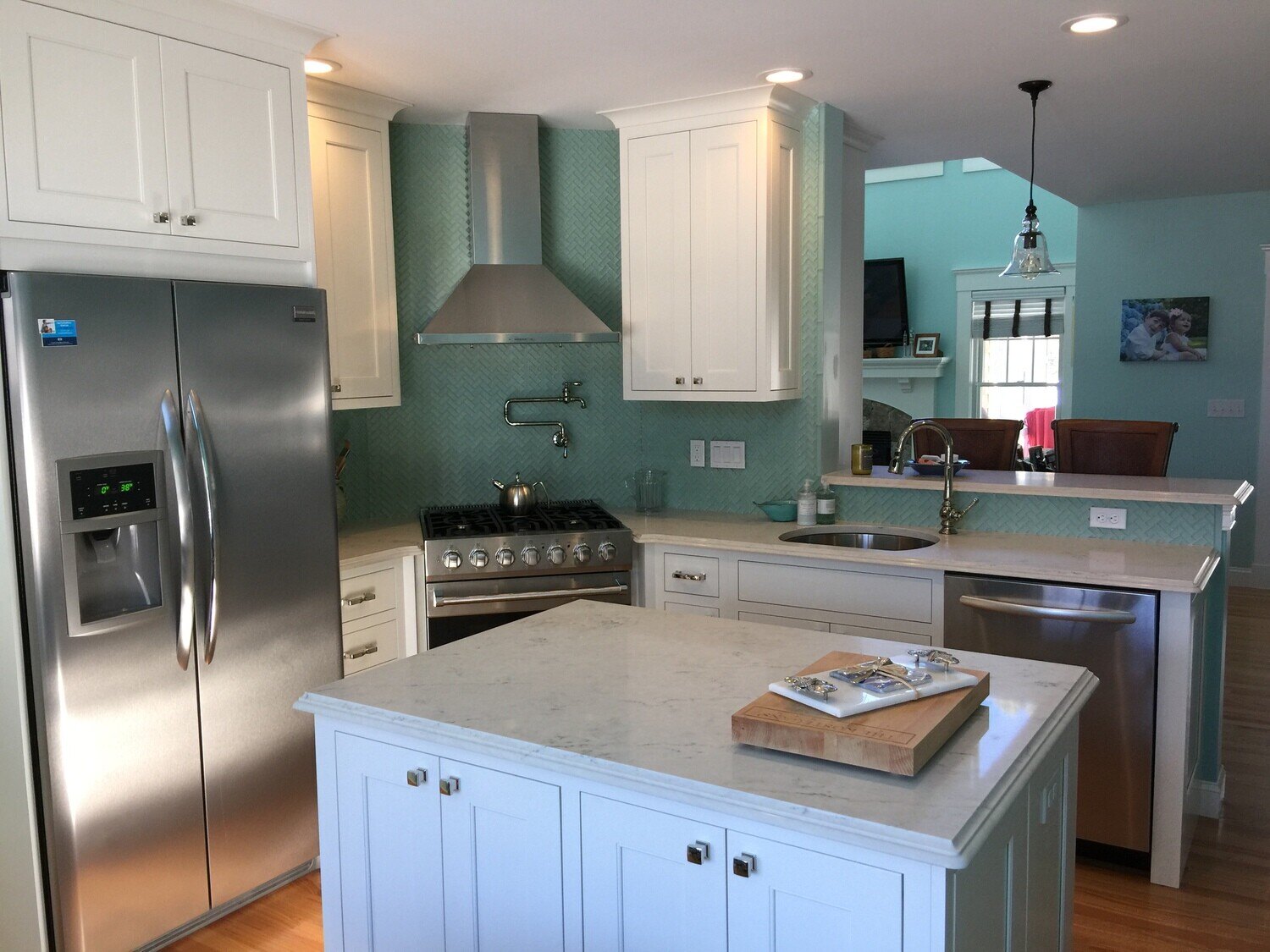 Open kitchen with stainless steel fridge and turquoise backsplash in Cotuit, remodeled by At Design Remodel