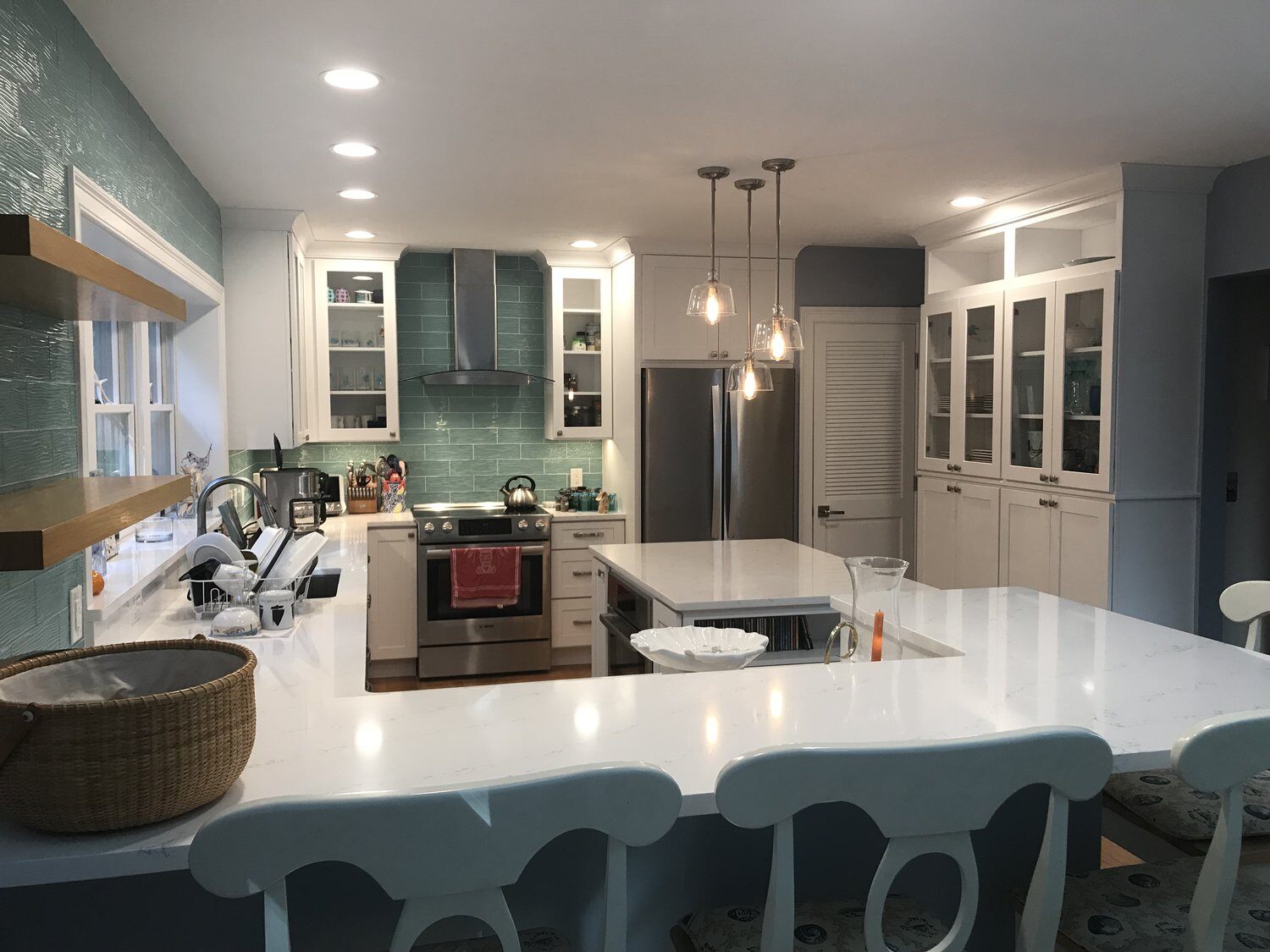 Kitchen remodel in Mashpee with teal backsplash and white island by At Design Remodel