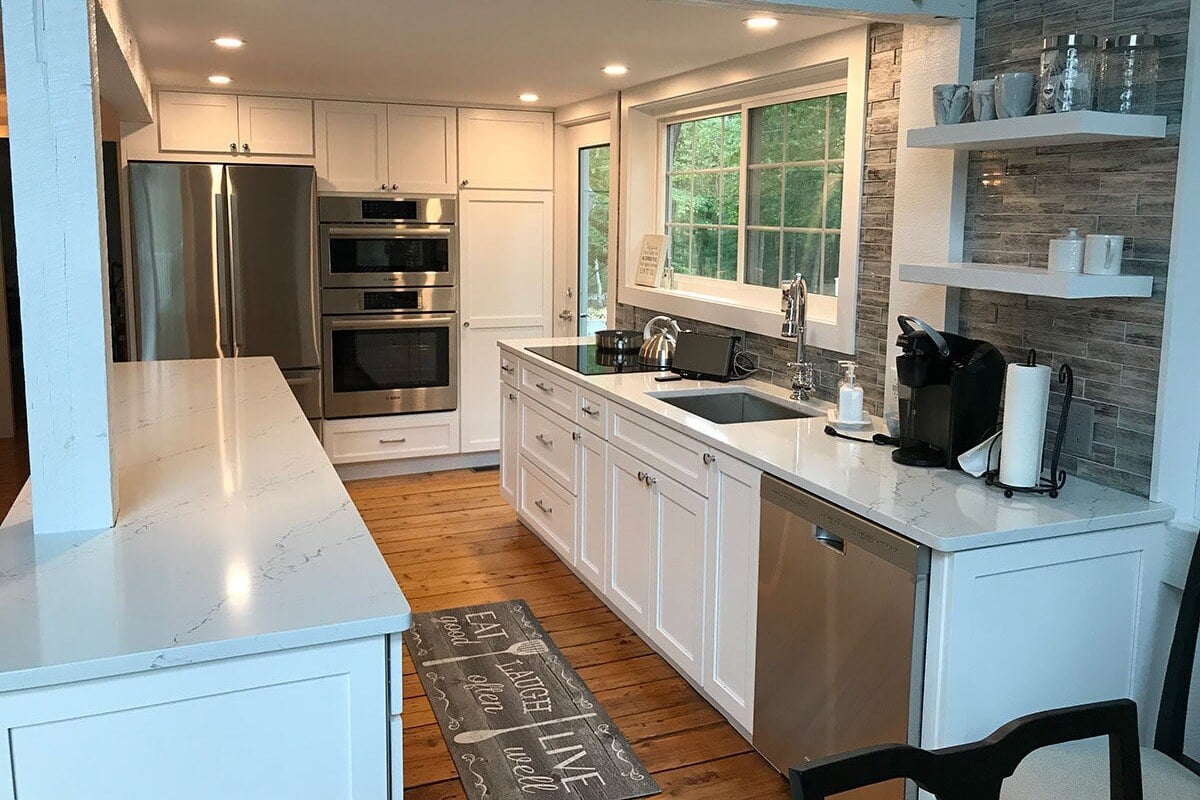 Modern kitchen remodel with white cabinetry, stainless steel appliances, and wooden floors in a Mashpee home