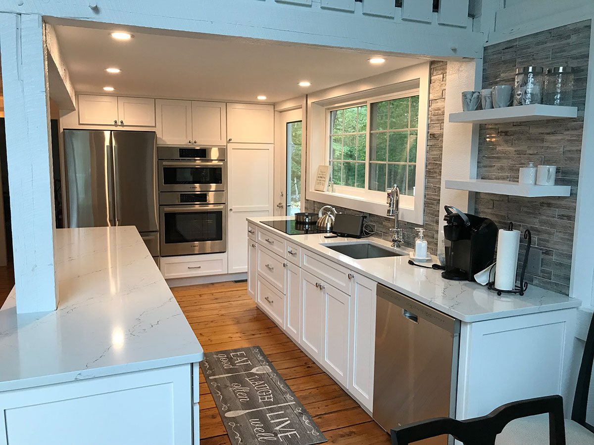 Modern kitchen remodel with white cabinetry, stainless steel appliances, and wooden floors in a Mashpee home