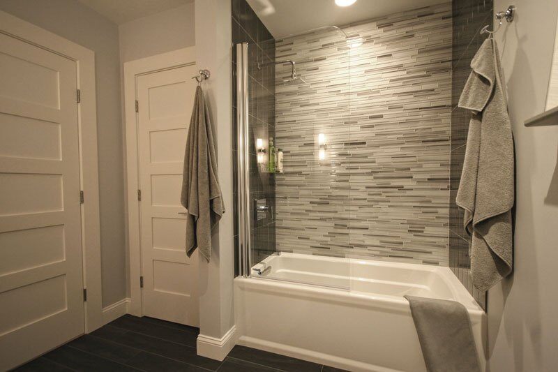 Modern bathroom with tiled shower and towels hanging, part of a Sandwich home renovation by At Design Remodel