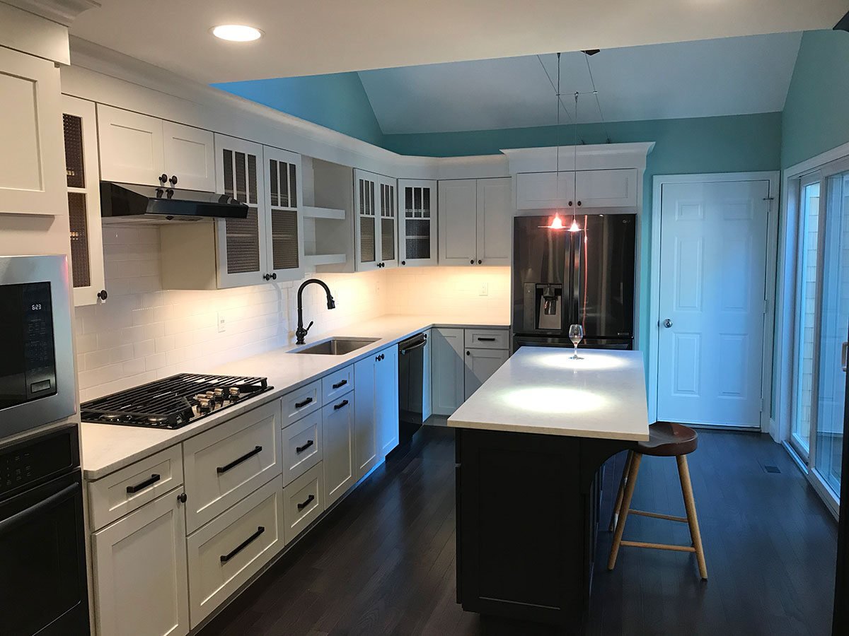 Spacious remodeled kitchen with white cabinets and island in Yarmouthport by At Design Remodel, Mashpee